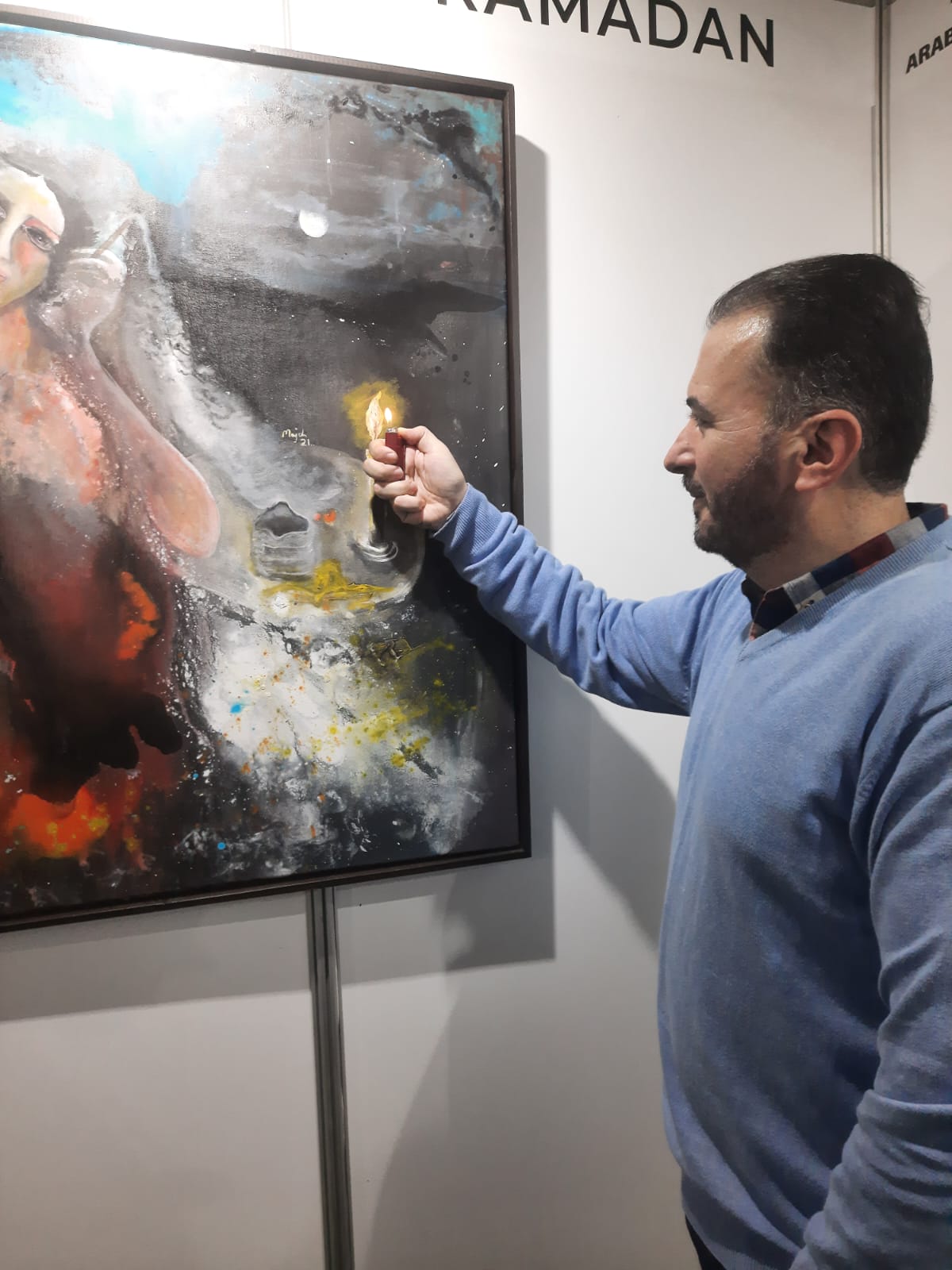رئيس ملتقى الألوان الفني الشاعر محمد علوش متفاعلا امام عمل للتشكيلية مجد رمضان